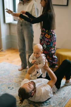 A delightful and joyful family scene unfolds with a baby happily being played with on the cozy living room floor