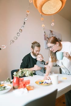 A truly joyful family moment together at home, sharing delicious food and heartfelt laughter with their baby