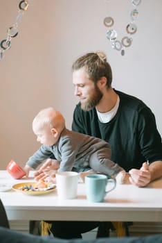 A heartwarming and delightful scene of a loving father interacting affectionately with his baby during breakfast time
