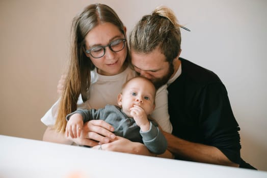 This heartwarming and delightful family portrait showcases parents lovingly and tenderly holding their baby