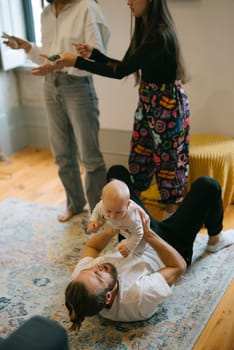 A really joyful moment filled with family interaction, showcasing an adorable baby and engaging adults surrounding them