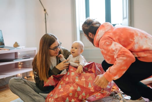 A heartwarming and joyful family moment as they unwrap gifts together with a baby, surrounded by love and laughter