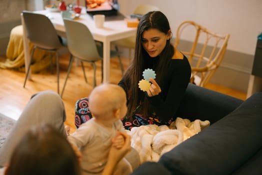 A caring adult offers colorful toys to an intrigued baby in a cozy space, encouraging joyful interaction