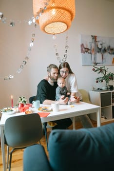 A joyful and heartwarming family moment featuring a baby at a beautifully set dining table filled with festive items