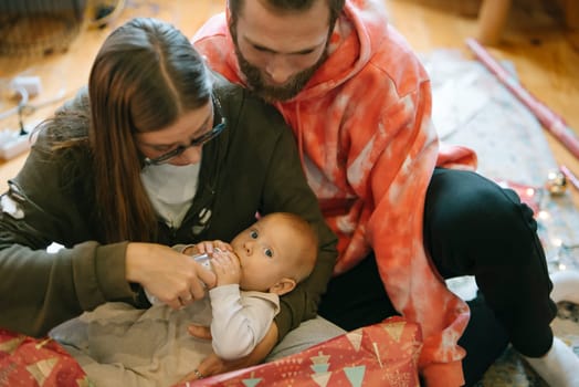 A precious family moment where parents lovingly care for their adorable baby amidst a cozy and joyful holiday setting