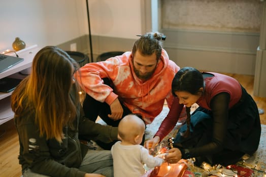 A cozy family scene featuring adults warmly interacting and engaging with a baby during a festive holiday occasion