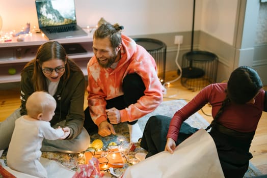 A delightful and joyful family moment featuring a baby, contagious laughter, and giftwrapping during a celebration