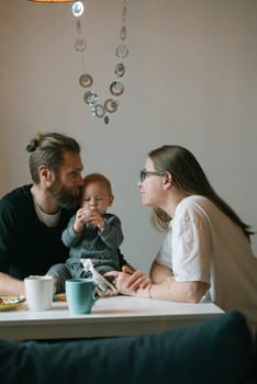 A lovely family is cherishing quality time together in the comfort of their home, enjoying coffee with their baby