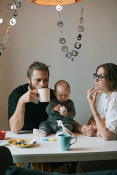 In a cozy setting, a loving family shares moments of joy while enjoying coffee and snacks with their baby