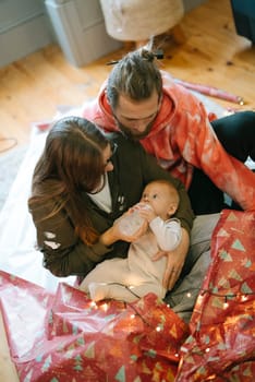 A truly heartwarming scene of a loving family caring for their adorable baby among vibrant festive decorations