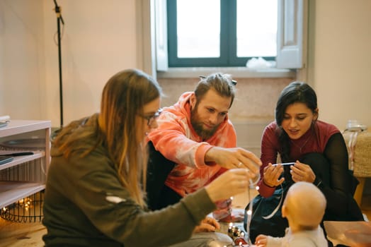 A heartwarming gathering of close friends who are joyfully enjoying quality time spent with a baby indoors
