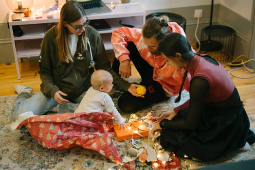 A loving family is enjoying precious quality time together, engaging playfully with a baby on a cozy floor setup