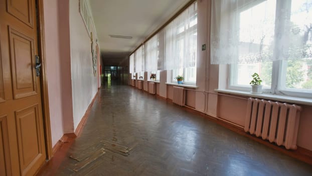 Strolling through a vintage school hallway on the eve of summer vacation, sunlight filters through the windows, creating a nostalgic play of light and shadow