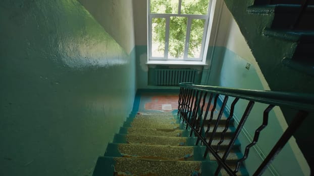 Staircase with chipped paint in an abandoned school building, sunlight streaming through window at the top