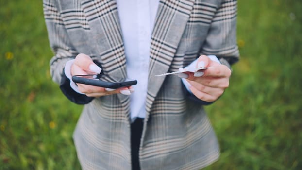 Professional woman working remotely, using smartphone and credit card while sitting outdoors