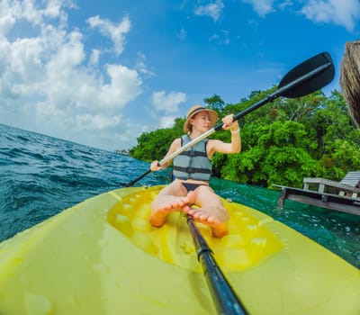 Unaltered woman tourist kayaking on the serene turquoise waters of Lake Bacalar, Mexico, surrounded by natural beauty. Adventure, relaxation, and outdoor travel concept in a peaceful tropical destination.