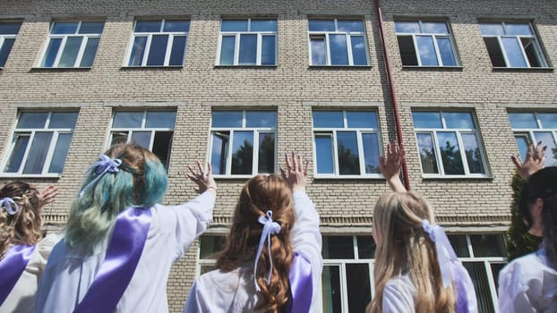 Female graduates waving goodbye to their school on their last day, celebrating the end of an era and the beginning of a new chapter