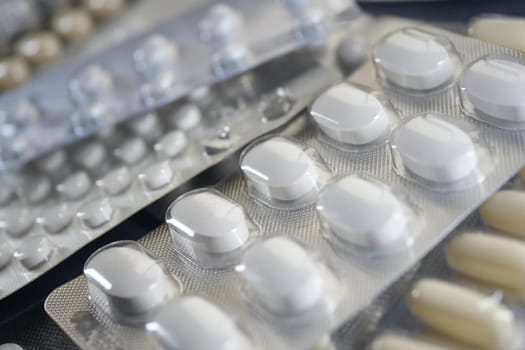 Various types of white tablets are arranged neatly in their blister packs. Some packs show indications of different sizes and shapes, set against a neutral background.