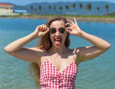 Bright blond young woman standing in sea and showing her tongue
