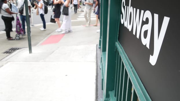 New York City, United States - 29 Aug 2023: Subway sign, underground metro station. Metropolitan entrance fence, public passenger transport exit, text signboard. Pedestrians people on Manhattan street