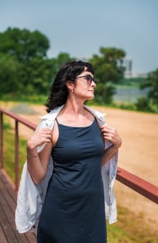 50 years old russian woman in short dress and sunglasses covering herself from the sun on the summer day