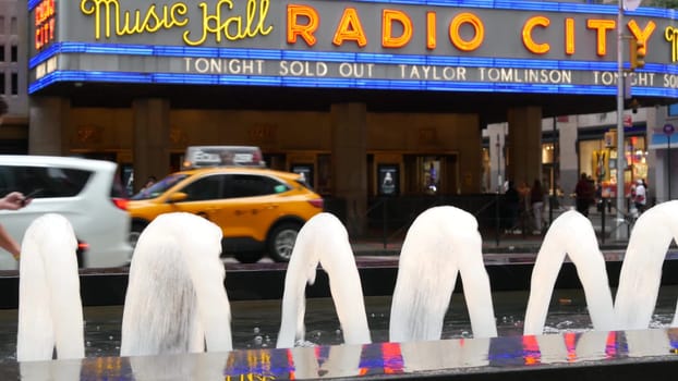 New York, United States - 10 Sept 2023: Manhattan Midtown street. Radio City Music Hall, Rockefeller Center, USA. People pedestrian, urban traffic, 6 Sixth Americas avenue crossroad, yellow taxi cab.