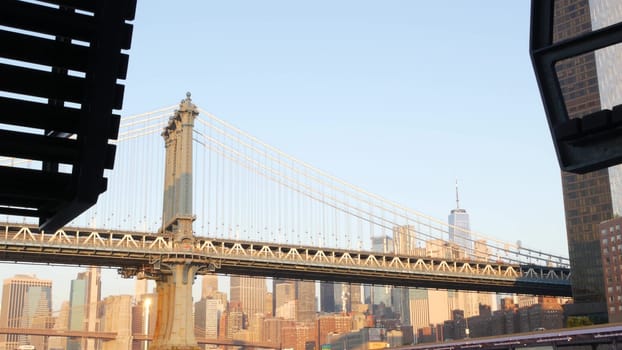 New York City, United States - 7 Sept 2023: Manhattan Bridge to Brooklyn. Pier 35 swings bench, waterfront downtown skyline cityscape. World Trade Center skyscraper, financial district morning sunset.
