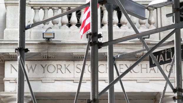 New York City, United States - 4 Sept 2023: Lower Manhattan Downtown Financial District architecture. Wall street road sign near Stock Exchange building, USA Stock Market. Scaffolding, American Flag.