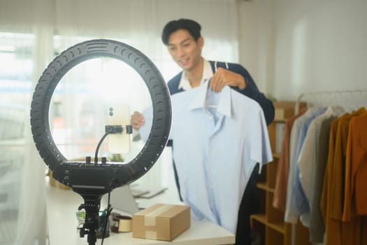 Young entrepreneur showcasing shirt in front of camera for an online sales event or live streaming.