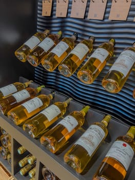 A collection of Sauternes wine bottles showcases their golden color and intricate labels, arranged on sleek shelving in a contemporary wine cellar, ideal for enthusiasts and collectors.