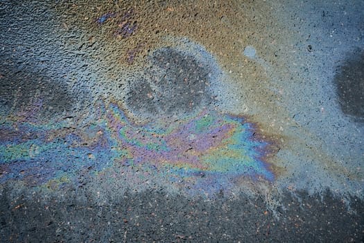 Close-up of colorful gasoline stains on the pavement, revealing the beautiful texture and hues that create a striking background.