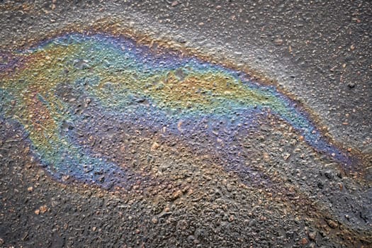 Close-up of vibrant oil spills on asphalt, highlighting the rich colors and textures that form an engaging background