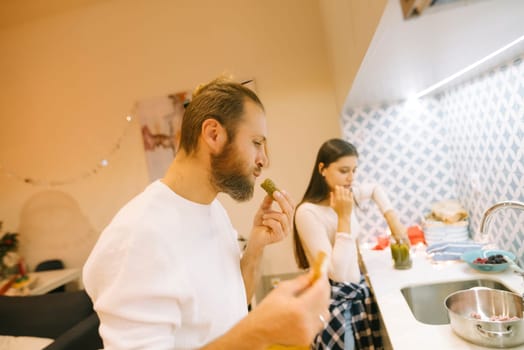 A couple enjoys delicious pickles in their stylish kitchen, sharing a delightful moment that highlights their intimacy