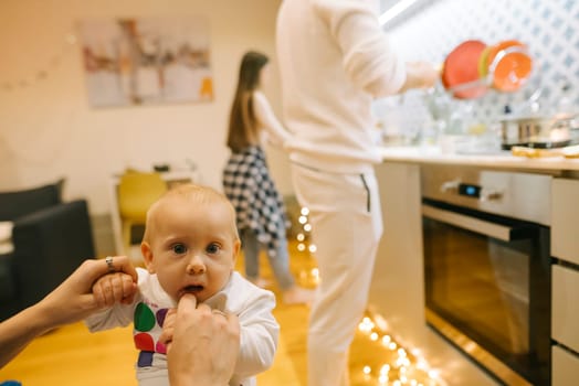 A heartwarming scene of a happy baby in a cozy kitchen surrounded by family members engaged in daily activities