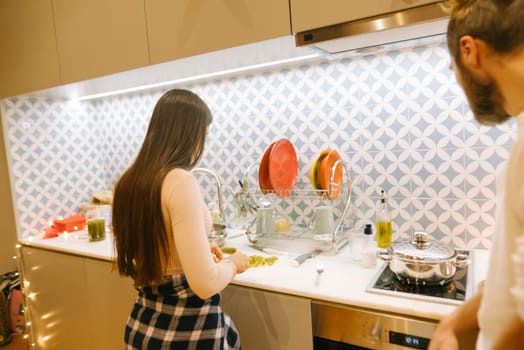 A couple enjoys cooking together in their modern kitchen, showcasing teamwork and warmth while preparing a meal