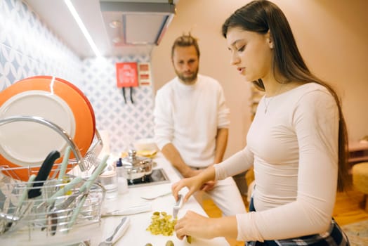 In a cozy kitchen filled with warmth, a couple joyfully cooks together, preparing a delicious meal for sharing