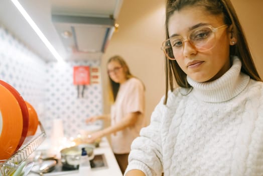 Two women happily enjoy the art of cooking in a cozy, stylish kitchen, sharing joyful moments and laughter together
