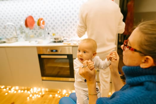 A heartwarming scene of a baby and caregiver joyfully sharing a delightful moment in a festive, cheerful kitchen