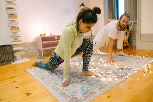 In a cozy room, a couple joyfully practicing yoga together improves fitness and strengthens their emotional bond