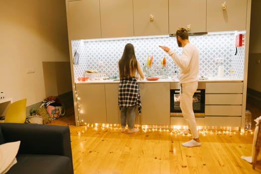 A loving couple is enjoying a cozy evening together as they cook delicious meals in a stylish kitchen ambiance