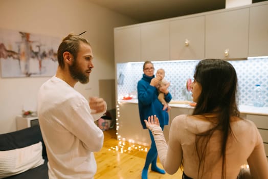 In a stylish and modern kitchen, a lively and joyful family gathering is taking place, with two adults and a baby