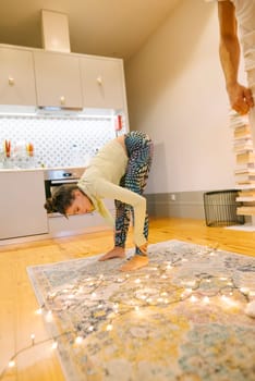 A young child joyfully performs various yoga poses at home, surrounded by festive decorations and cozy, warm lighting