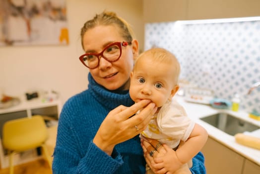 A caring and loving mother enjoys spending quality time with her adorable baby in a stylish kitchen setting