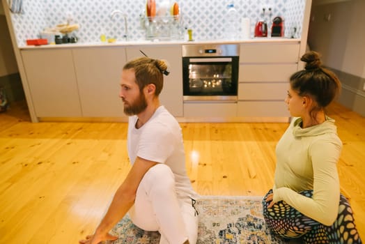 Two individuals engaging in yoga practice in a stylish and modern kitchen space, enhancing their focus and mindfulness