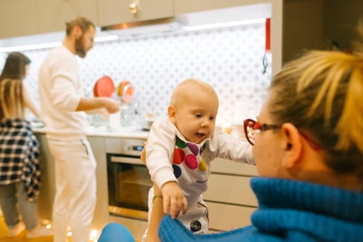 A joyful family moment unfolds in a modern kitchen with a baby and both parents happily cooking together