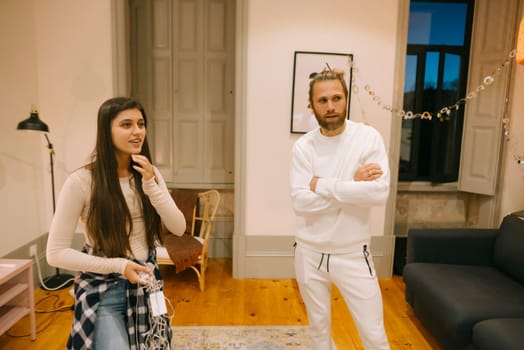 Two young adults are engaged in a relaxed and easygoing conversation in a stylish and cozy indoor setting