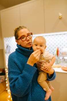 A beautifully warm scene of a loving mother nurturing her adorable baby in a stylish and modern kitchen environment