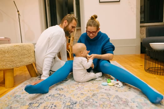 A joyful family enjoys playtime on a cozy rug, engaging with their adorable baby in a relaxed setting