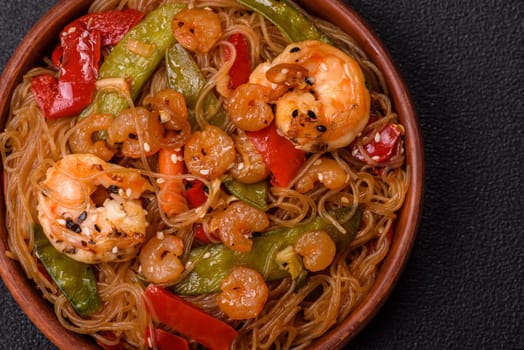 Glass noodles with shrimps and seafood, vegetables, spices and soy sauce on dark concrete background