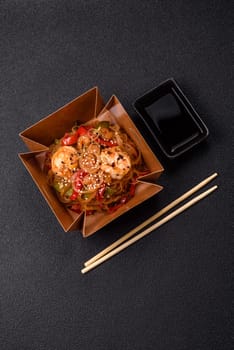 Glass noodles with shrimps and seafood, vegetables, spices and soy sauce on dark concrete background